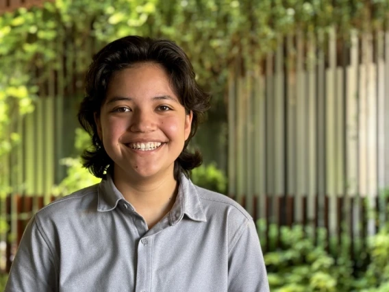 Illana Valenzuela in a gray shirt facing the camera with ENR2 vines and building in the background.
