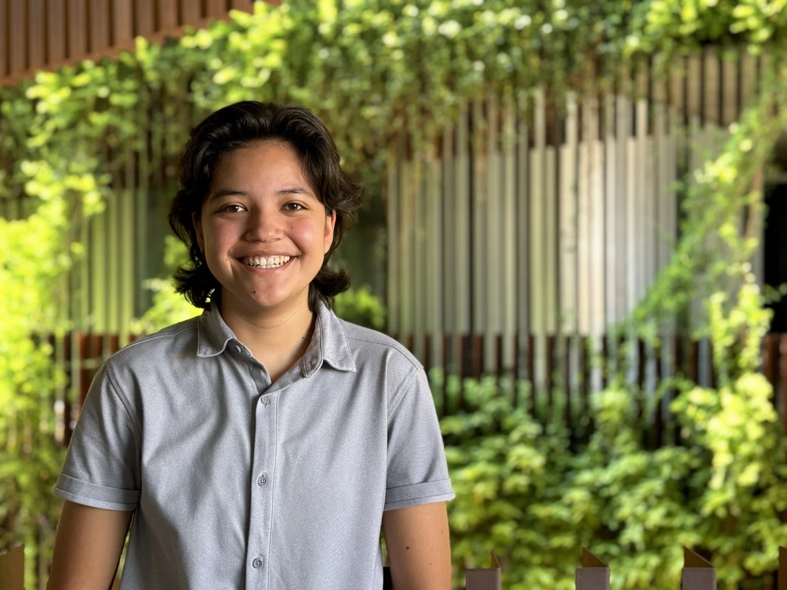 Illana Valenzuela in a gray shirt facing the camera with ENR2 vines and building in the background.